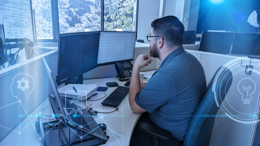 Employee checks cyber network for issues via computer monitor.