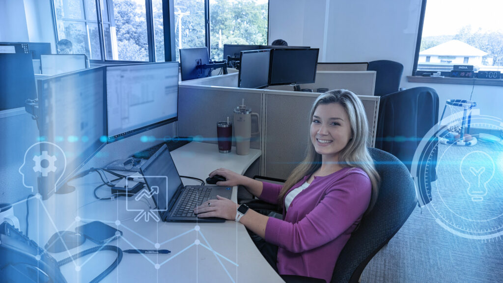 Smiling ProWriters Agent sits in front of computer monitors at her workstation.