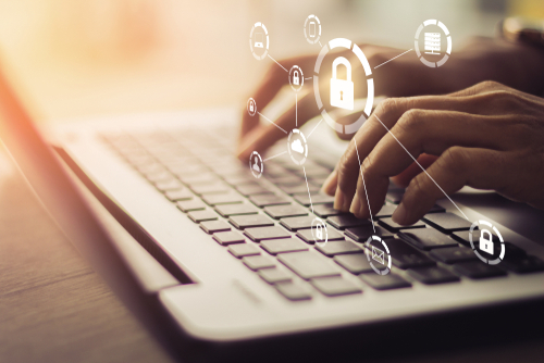 Close up of hands typing on a laptop keyboard with graphics of padlocks overlaying the image. 