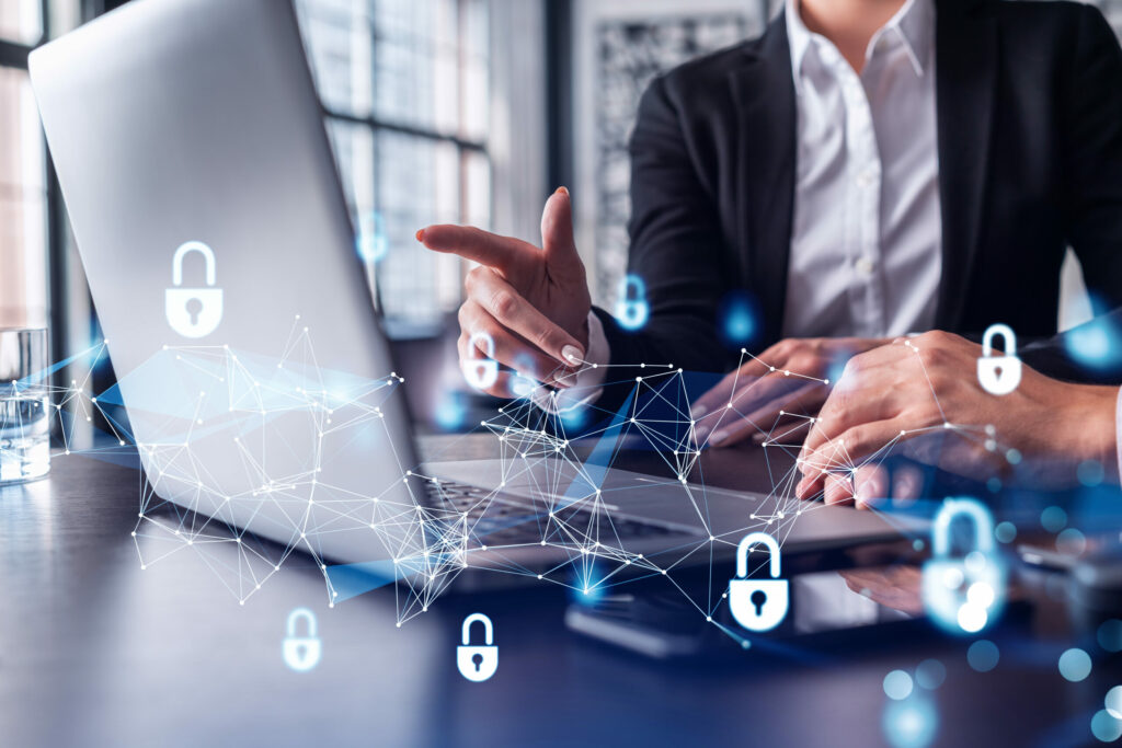  Insurance broker points to laptop screen, explaining a Cyber Insurance policy form to client, photo overlaid with padlock graphics. 
