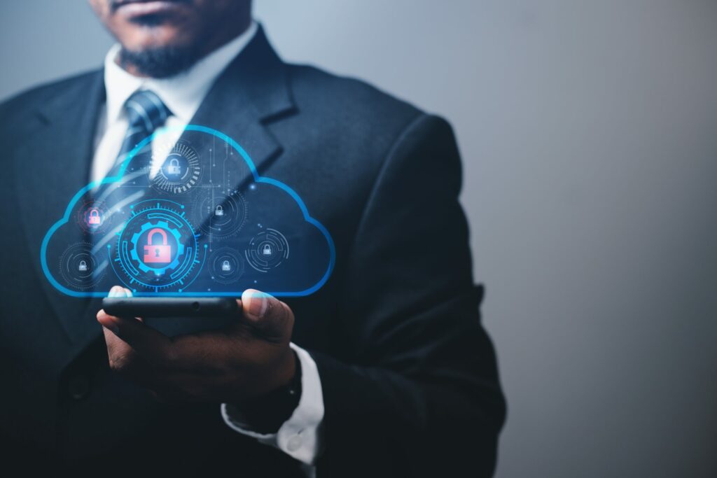  Insurance broker in business suit holds smartphone, overlaid with graphic illustrating cyber security in cloud computing. 