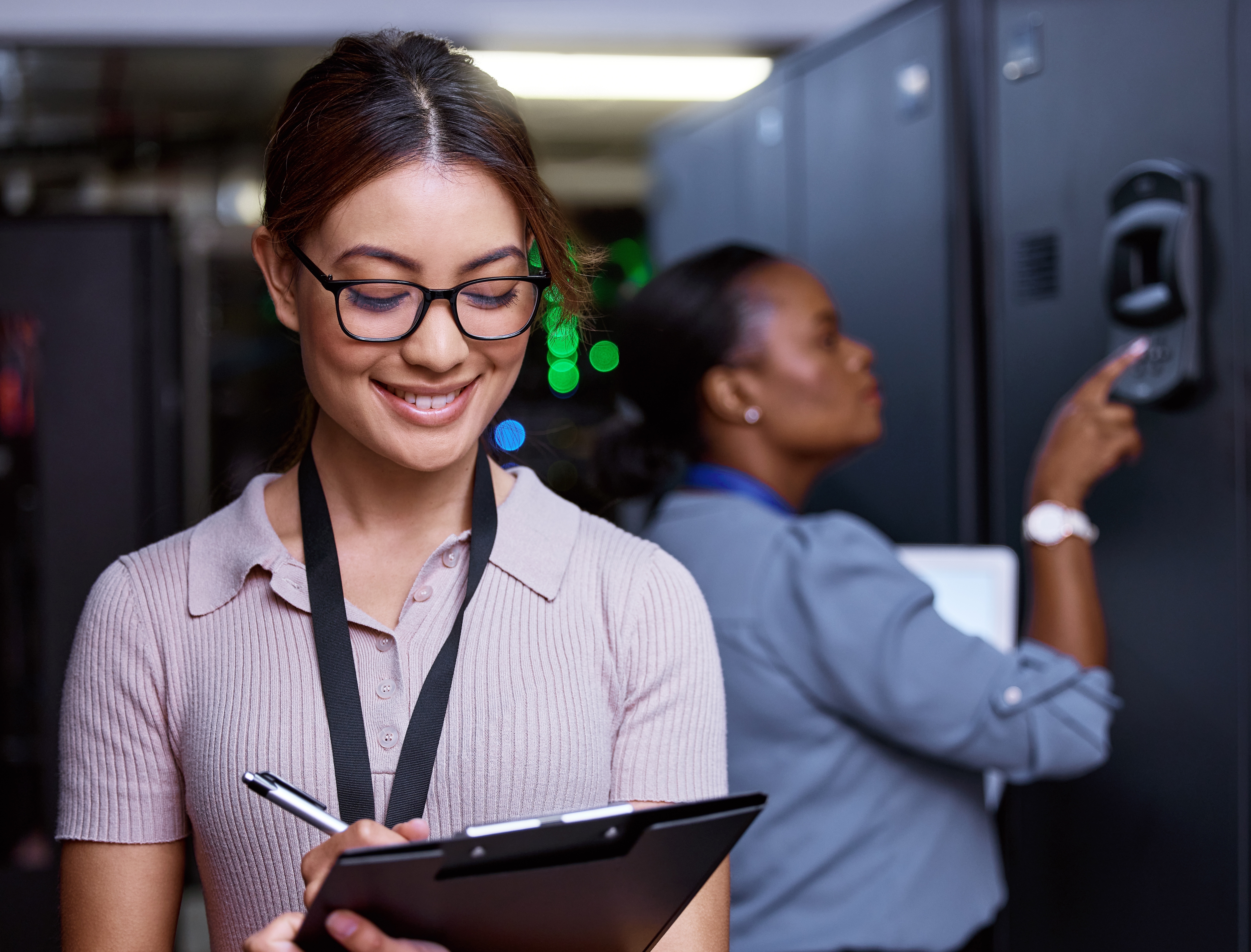 Smiling cyber security specialist checks off updates to her company’s data security in the server room.