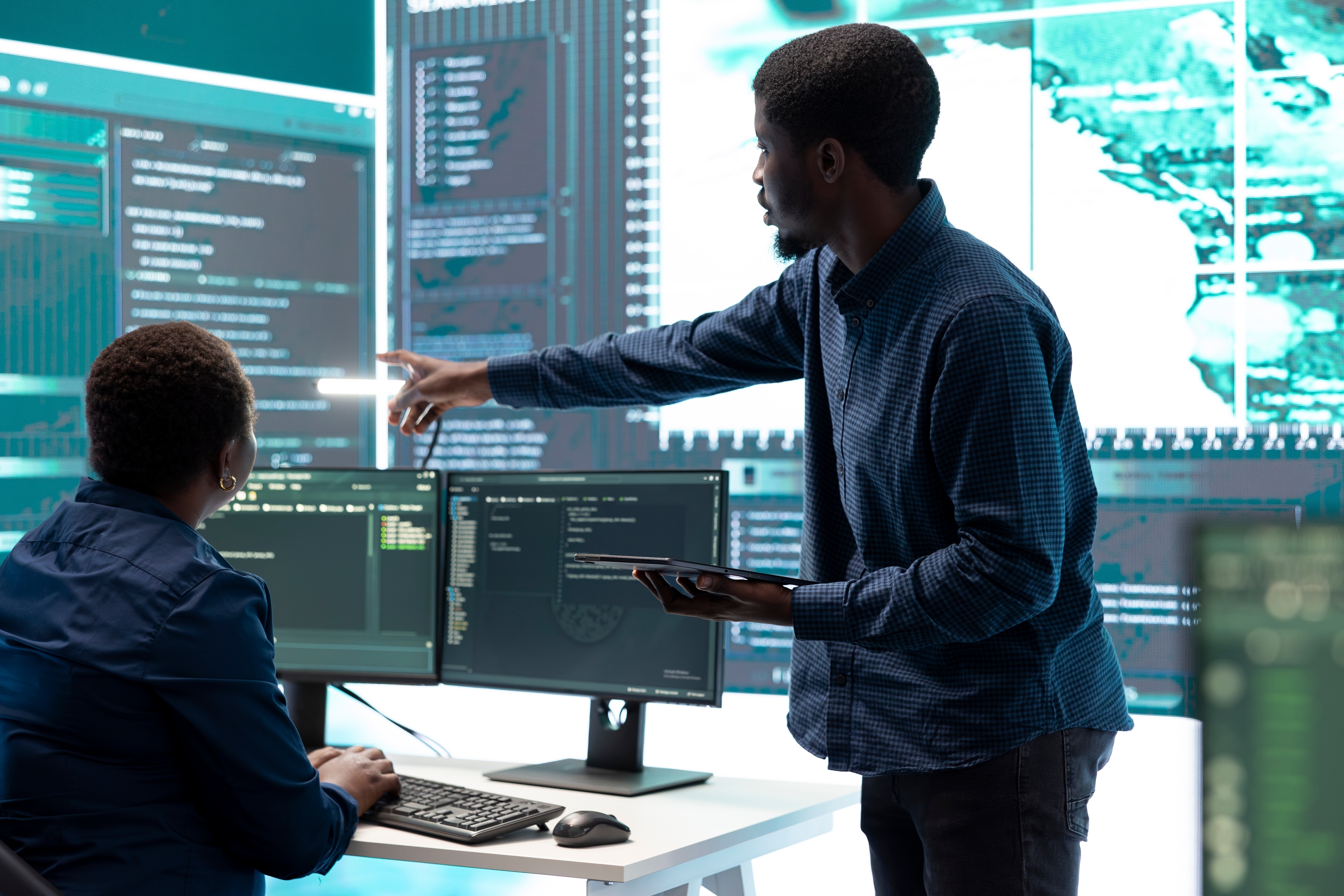Two cyber security experts analyzing data on multiple screens during a data breach forensics investigation in a high-tech control room.