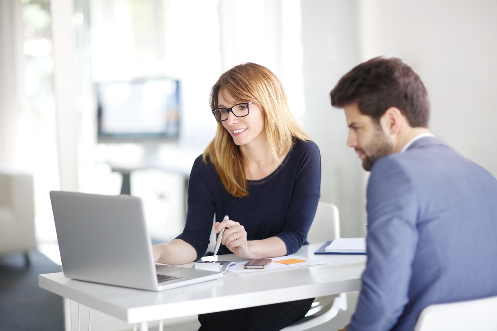  Female insurance agent discusses cyber insurance policy with male business client. 